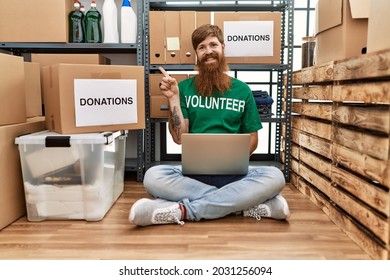 Caucasian Man With Long Beard Wearing Volunteer T Shirt Using Laptop Smiling Happy Pointing With Hand And Finger To The Side 