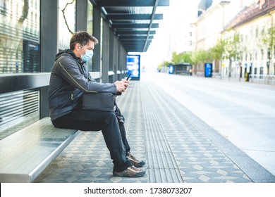 Caucasian man, with mask on his face sitting at a bus stop, using a mobile and waiting for a public transportation - Powered by Shutterstock - Get 15% off with code: PIKWIZARD15