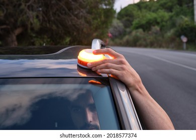 Caucasian man placing the new Emergency Light for damaged vehicles (V16 luminous beacon), which must be replaced by triangles. road safety. - Shutterstock ID 2018577374