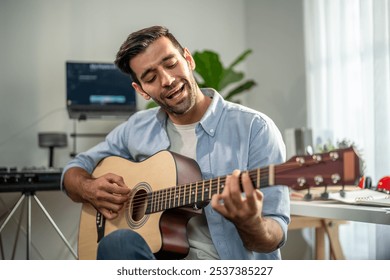 Caucasian man play guitar and produce electronic soundtrack at home. Attractive male artist musician composing, create new song using musical instrument and audio equipment in recording music studio. - Powered by Shutterstock