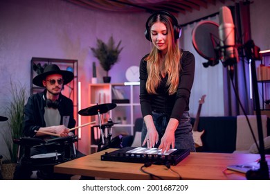 Caucasian man playing electronic drums while woman mixing sound on equalizer. Talented duo of musicians working on new song at professional music studio. - Powered by Shutterstock