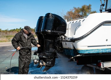 Caucasian man pressure washing outboard motors on power boat