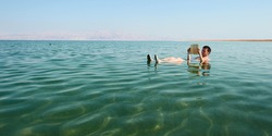 高加索人读一本书漂浮在死海在以色列的水域