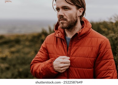 Caucasian man in a red jacket stands outdoors. White man in the red jacket is zipping up. The red jacket wear by man with the natural background. Outdoor fashion. Clothing brand for outdoor activity - Powered by Shutterstock