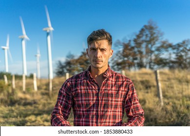 Caucasian Man In Red Plaid Shirt Posing In A Wind Farm

