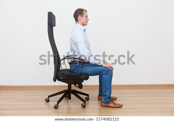 正しい姿勢で椅子の端に座っている白人 の写真素材 今すぐ編集
