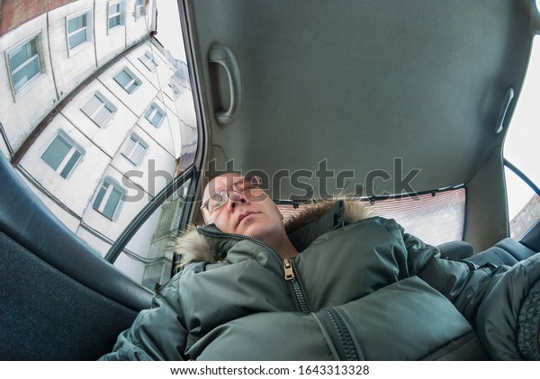 a caucasian man\
sleeps in a car back seat