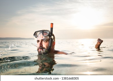 Caucasian man snorkelling,floating on the surface,spitting out water with a funny goofy facial expression,summer seaside vacation activity,cancelled due to Coronavirus COVID-19 global pandemic crisis