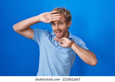 Caucasian Man Standing Over Blue Background Smiling Cheerful Playing Peek A Boo With Hands Showing Face. Surprised And Exited 