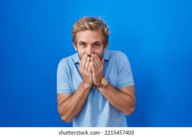 Caucasian Man Standing Over Blue Background Laughing And Embarrassed Giggle Covering Mouth With Hands, Gossip And Scandal Concept 