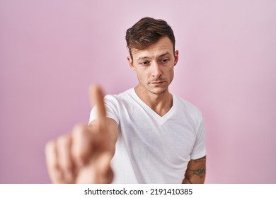 Caucasian Man Standing Over Pink Background Pointing With Finger Up And Angry Expression, Showing No Gesture 