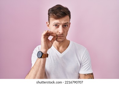 Caucasian Man Standing Over Pink Background Mouth And Lips Shut. Secret And Silent, Taboo Talking 