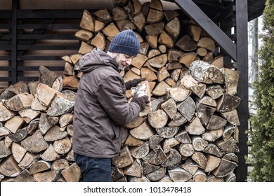 Caucasian man taking firewood from woodshed - winter or autumn country lifestyle.