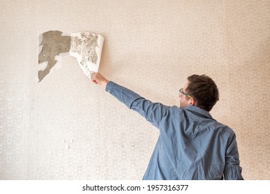 Caucasian Man Tearing Off Old Wallpaper From Wall Preparing For Home Redecoration