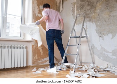 Caucasian Man Tearing Off Old Wallpaper From Wall Preparing For Home Redecoration