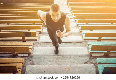 Caucasian man trains in running on the stairs. Track and field runner in sport uniform training outdoor. athlete, top view. step exercises. - Shutterstock ID 1384926236