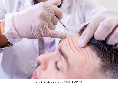 Caucasian man undergoing beauty spa botulinum neurotoxin Botox treatment for anti-aging, to smooth wrinkles as a cometic solution. Injecting forehead to relax muscles with a non-invasive procedure.