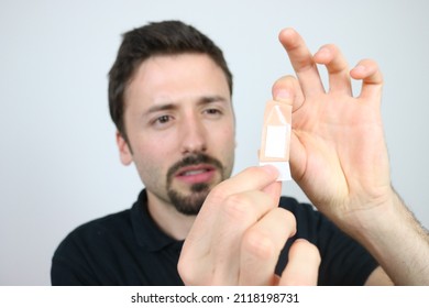 Caucasian Man Is Unwrapping Adhesive Bandage