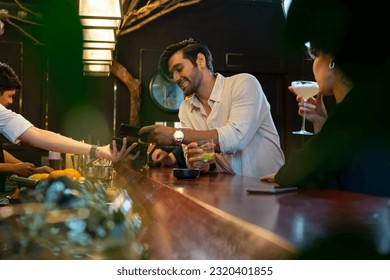 Caucasian man using mobile banking application on smartphone scan QR code making online payment while hangout party at restaurant bar. Electronic banking and Contactless payment technology concept. - Powered by Shutterstock