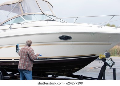 Caucasian man washing boat hull with brush