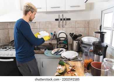 Caucasian Man Washing Dishes In His Messy Kitchen. Copy Space