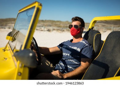 Caucasian Man Wearing Face Mask And Sunglasses Sitting In Beach Buggy. Beach Stop Off On Summer Holiday Road Trip During Coronavirus Covid 19 Pandemic.