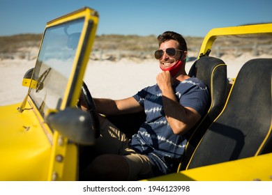 Caucasian Man Wearing Face Mask Sitting In Beach Buggy Smiling. Beach Stop Off On Summer Holiday Road Trip During Coronavirus Covid 19 Pandemic.