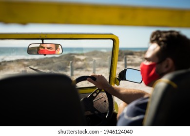 Caucasian man wearing face mask sitting in beach buggy reflected in mirror. beach stop off on summer holiday road trip during coronavirus covid 19 pandemic. - Powered by Shutterstock