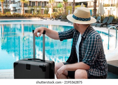 Caucasian Man Wearing Sunhat With Suitcase, Baggage Coming To Hotel, Looking At Empty Swimming Pool,no People.Tired Travelling Tourist Arriving At Hotel On Vacation,holidays,arrival Concept.Back View.