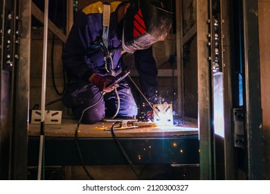 A Caucasian Man Welding Metal Inside An Elevator Under Construction