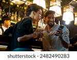 Caucasian man and woman using mobile phone for online booking or making payment during hanging out nightlife party at restaurant bar. People enjoy meeting nightlife celebration party at nightclub.