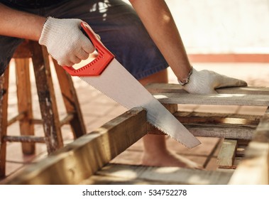 Caucasian man working cutting plank with handsaw. Carpentry, construction. 