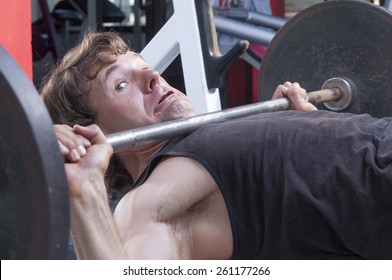 Caucasian Man Working Out In Gym Is Stuck Under Heavy Barbell On Bench Press