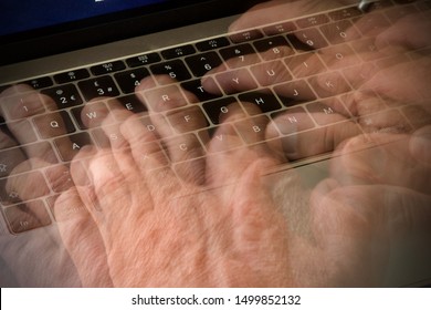 Caucasian mans hand typing on a laptop keyboard, blurred and showing movement