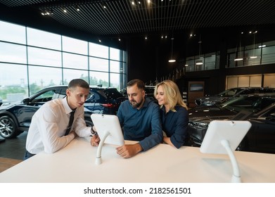 Caucasian Married Couple Chooses A Car In A Car Dealership On Digital Tablets. 