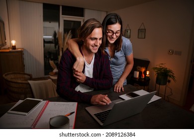 Caucasian Married Couple Working Late At Night In Lounge Showing Affection 