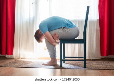 Caucasian mature man doing childs pose in yoga using chair
