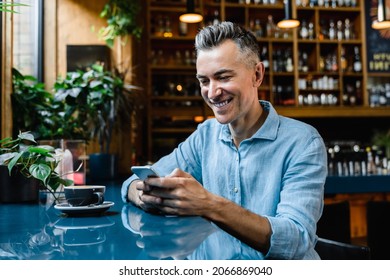 Caucasian mature middle-aged businessman boss freelancer relaxing in cafe restaurant drinking coffee and using cellphone for e-banking e-commerce, online shopping