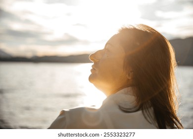 Caucasian mature woman enjoying sunset by lake - Powered by Shutterstock