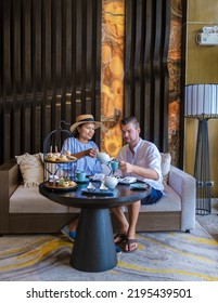 Caucasian Men And Asian Women Having A Luxury High Tea With Snacks And Tea In A Luxury Hotel