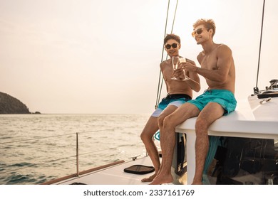 Caucasian men friend drinking champagne while having party in yacht. Attractive handsome male tourist hanging out celebrate holiday vacation trip while catamaran boat sailing during summer sunset. - Powered by Shutterstock