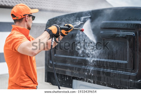 Caucasian Men in His 40s\
Pressure Washing Back of His Truck Cabin in a Car Wash. Vehicle\
Maintenance.