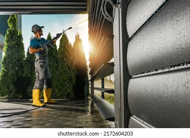 Caucasian Men in His 40s Washing His Modern Aluminium Carport Using Powerful Pressure Washer. Small Architecture Maintenance.