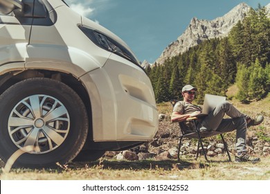 Caucasian Men with Modern Laptop Computer in His Hands Working Remotely While Camping in RV Camper Van Motorhome. High Mountains Landscape in a Background. Work and Travel Theme.  - Shutterstock ID 1815242552