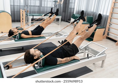 Caucasian men and woman training pilates with pilates equipment in fitness studio	 - Powered by Shutterstock