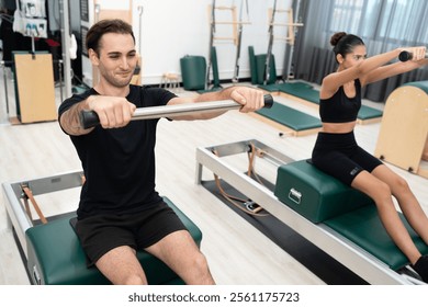 Caucasian men and woman training pilates with pilates equipment in fitness studio - Powered by Shutterstock