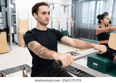 Caucasian men and woman training pilates with pilates equipment in fitness studio - Powered by Shutterstock