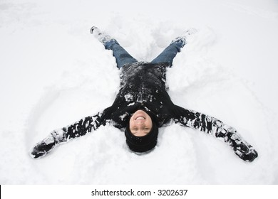 Caucasian Mid Adult Woman Making A Snow Angel In The Snow.