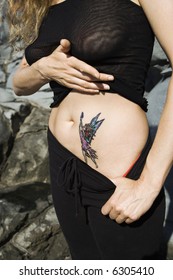 Caucasian Mid-adult Woman Revealing Tattoo Of Fairy On Stomach.