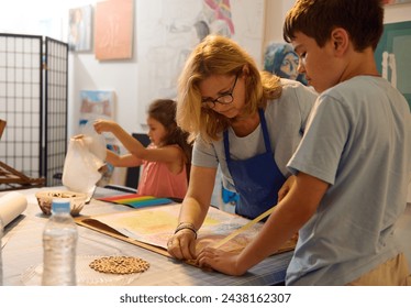 Caucasian middle aged woman, artist painter educator works with children, teaching art in the development center. People. Visual art. Education - Powered by Shutterstock